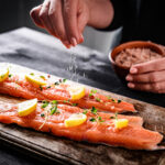 Woman seasoning salmon using a custom spice mix