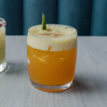 The "All Bark, No Bite" pineapple mocktail in a glass with a pineapple garnish on a table.