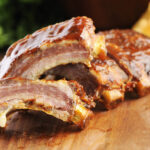 Grilled sliced barbecue pork ribs on a wooden background.