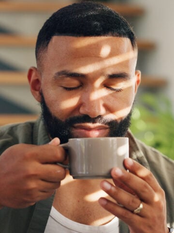 Calm man with drink by window in apartment